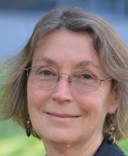 headshot photo of Dr. Karen Hamilton smiling with medium length light brown hair with gray in it and wearing thin wire rimmed glasses