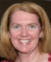 Kelly McMorrow smiling with medium length dirty blonde hair wearing a brown headband and a pink patterned top