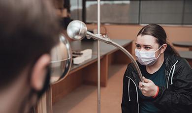 Students conduct a demonstration using a Van de Graaff generator.