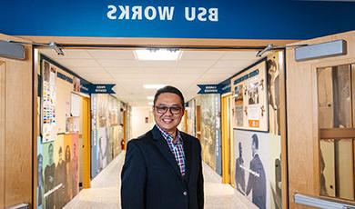 Gerald Tang stands in a hallway below a BSU Works sign